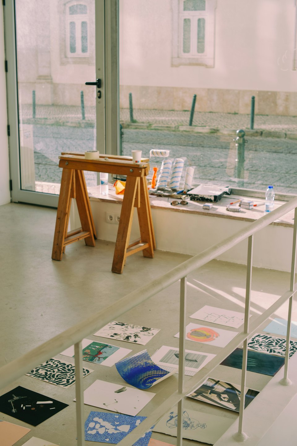 Art studio with supplies on concrete floor and window view.