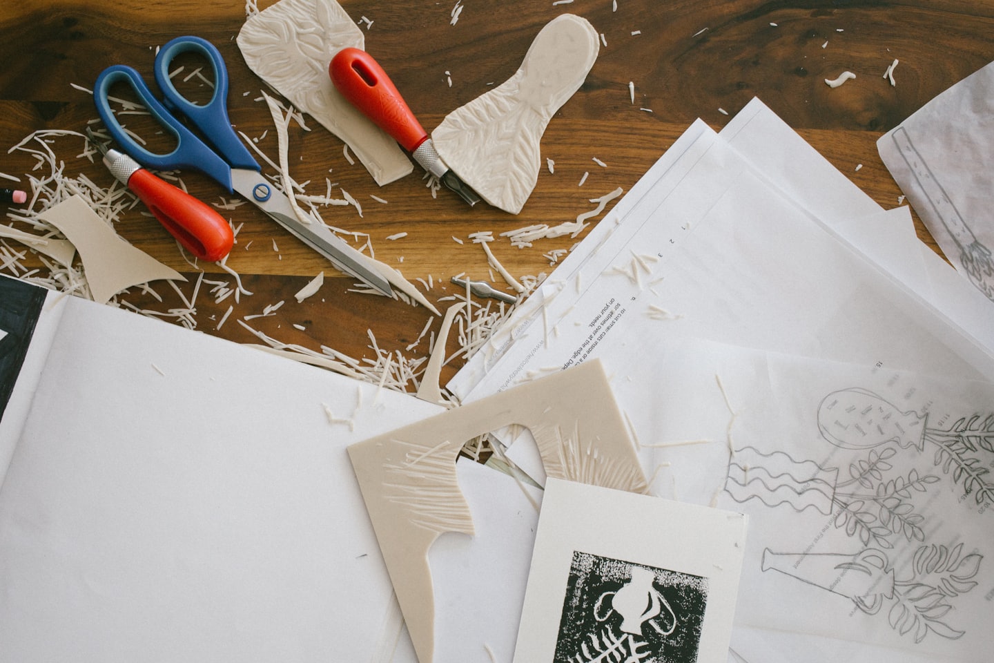 Linocut printing tools and materials on a wooden table.