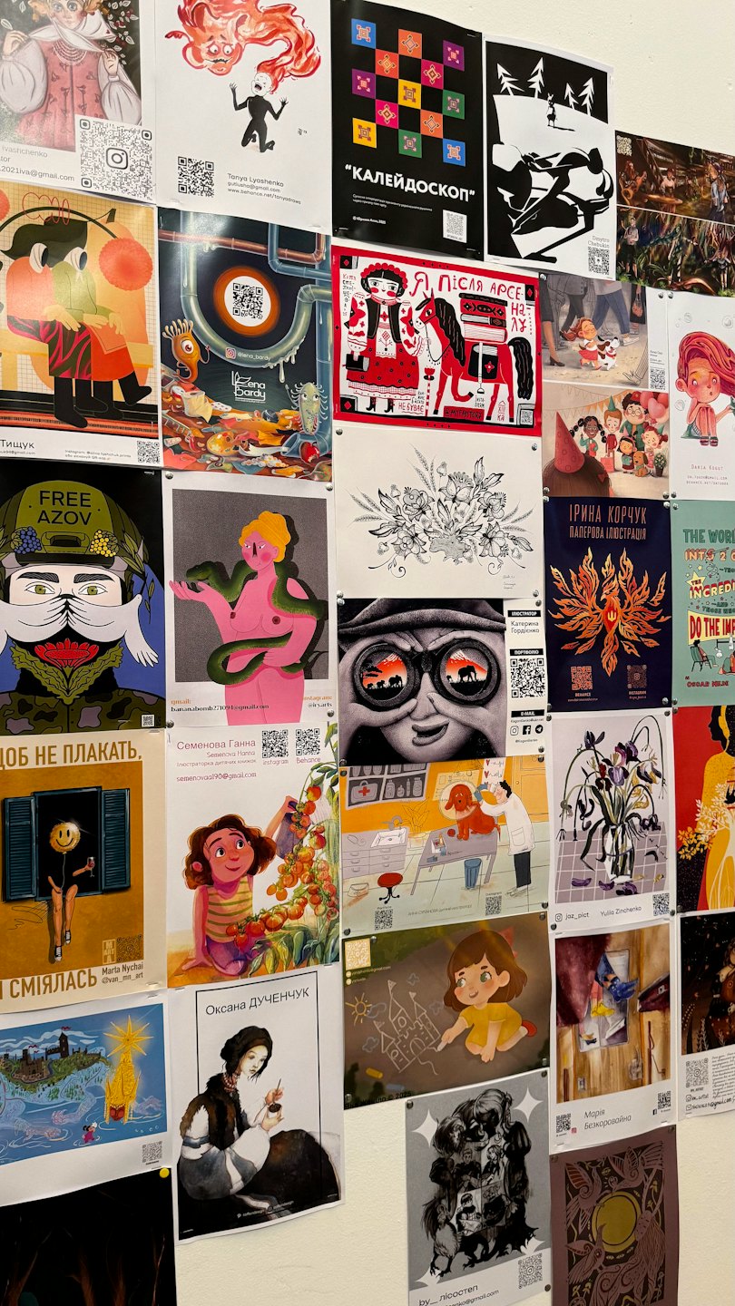A white wall covered in diverse artistic posters and illustrations.