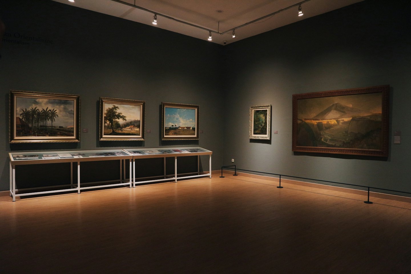 Empty art gallery showcasing multi-medium artwork on grey walls.